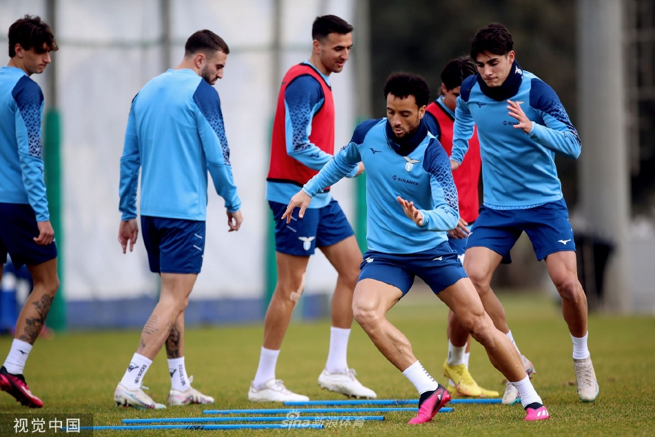 拉齐奥主教练萨里神情专注，在训练场边手持战术板，向身旁的助理教练指点部署，阳光洒在绿茵场上，映照出他深邃的思考面容。