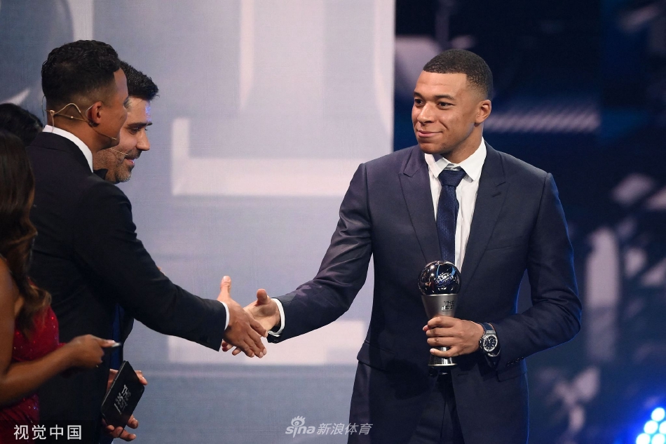 法国前锋本泽马身着优雅西装，神情轻松地与友人交流，展现出道别皇家马德里前最后的巅峰风采