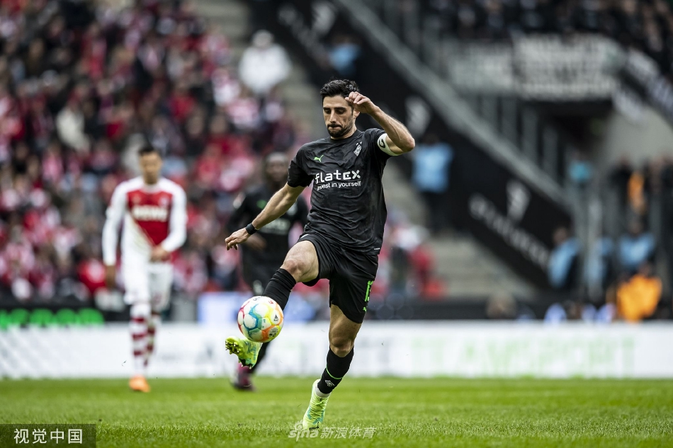 夕阳映照下的莱茵能源体育场全景，看台上交织着科隆标志性的红白两色