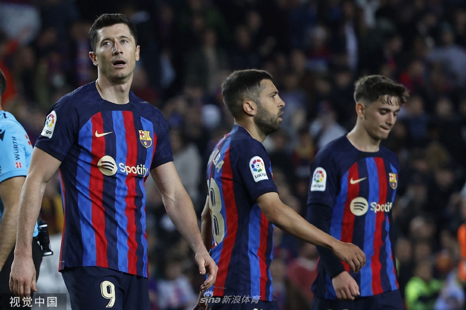 诺坎普夜空下，巴萨前锋莱万多夫斯基带球突进，赫罗纳后卫紧追不舍形成夹击之势