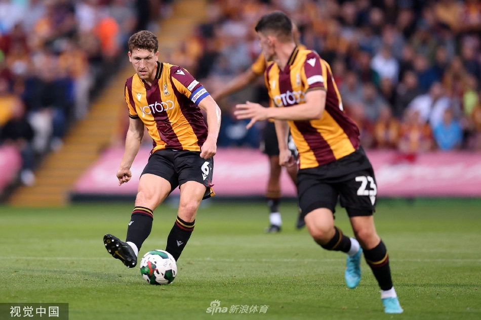 布莱克本球员庆祝进球，他张开双臂狂奔向角旗区，脸上是狂喜与释放，身后追赶而来的队友跃起准备拥抱，背景是模糊的绿色草坪与看台。