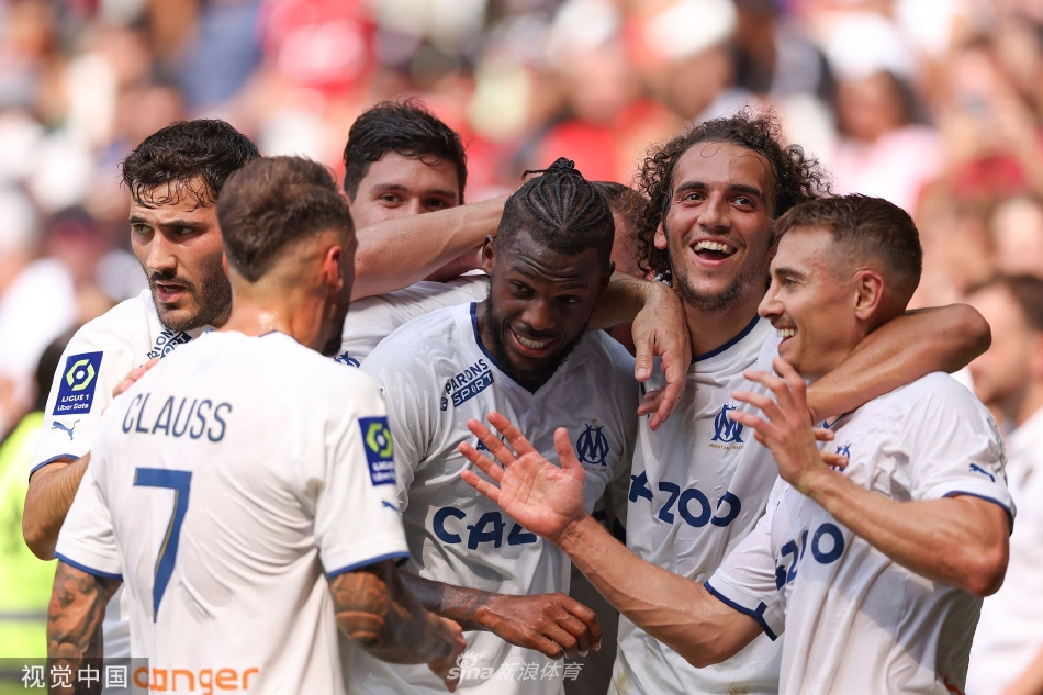 马赛前锋亚历克西斯·桑切斯在破门后张开双臂，面向看台激情庆祝，他的身影在球场的灯光下显得充满力量。