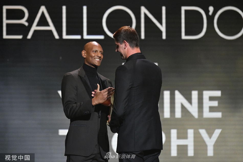 库尔图瓦与金球奖得主本泽马一同载誉归来，在皇马训练基地开心合影，共同展示奖杯。