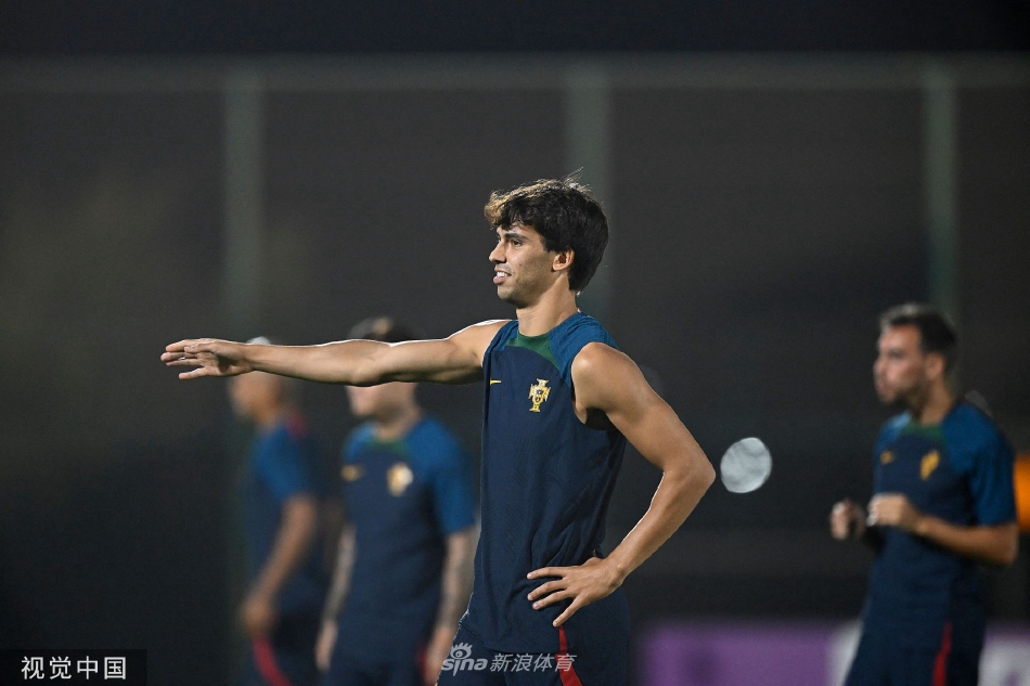 球员们在开阔的训练场上进行拉伸与有球热身，远处是卡塔尔独特的现代化建筑天际线。