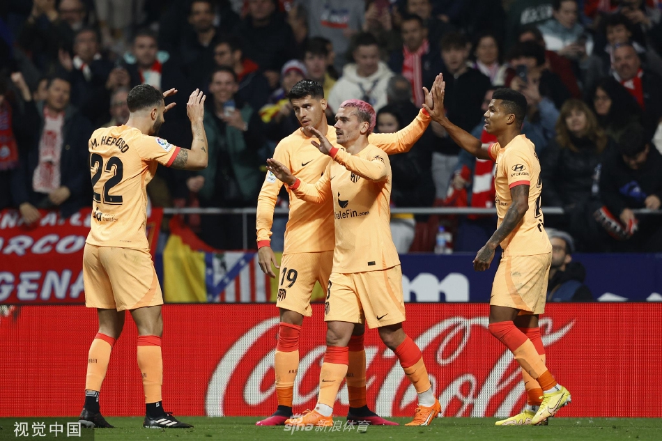 格列兹曼射门动作特写，他摆腿瞬间的身体姿态协调而充满力量，目光紧紧锁定飞出的皮球，身后是试图封堵却望尘莫及的毕尔巴鄂后卫。