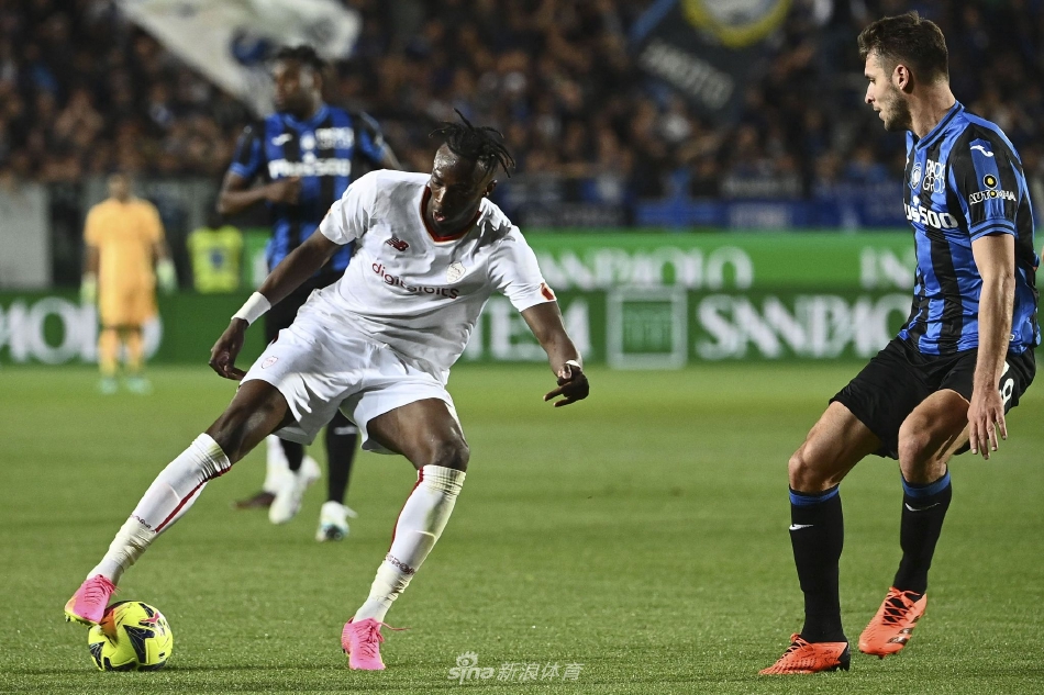 比赛中双方球员激烈拼抢高空球，肌肉碰撞力量感十足，背景是清晰可见的球场广告与模糊的狂热观众席。