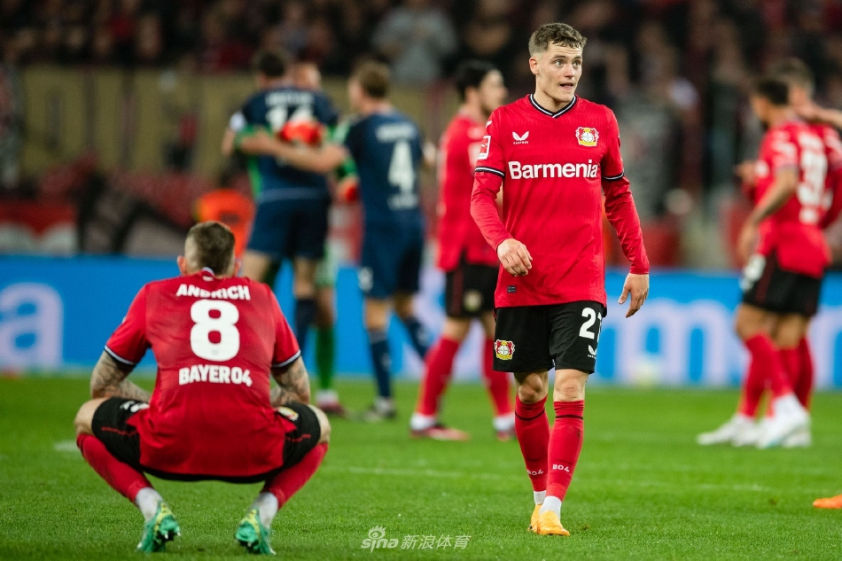 勒沃库森前锋在科隆后卫贴身紧逼下艰难起脚，皮球划过一道弧线飞向球门