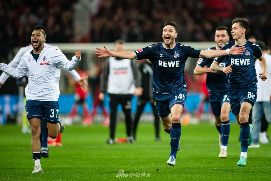 科隆球员进球后狂奔至角旗区，张开双臂激情滑跪庆祝，身后是欢呼的绿色身影