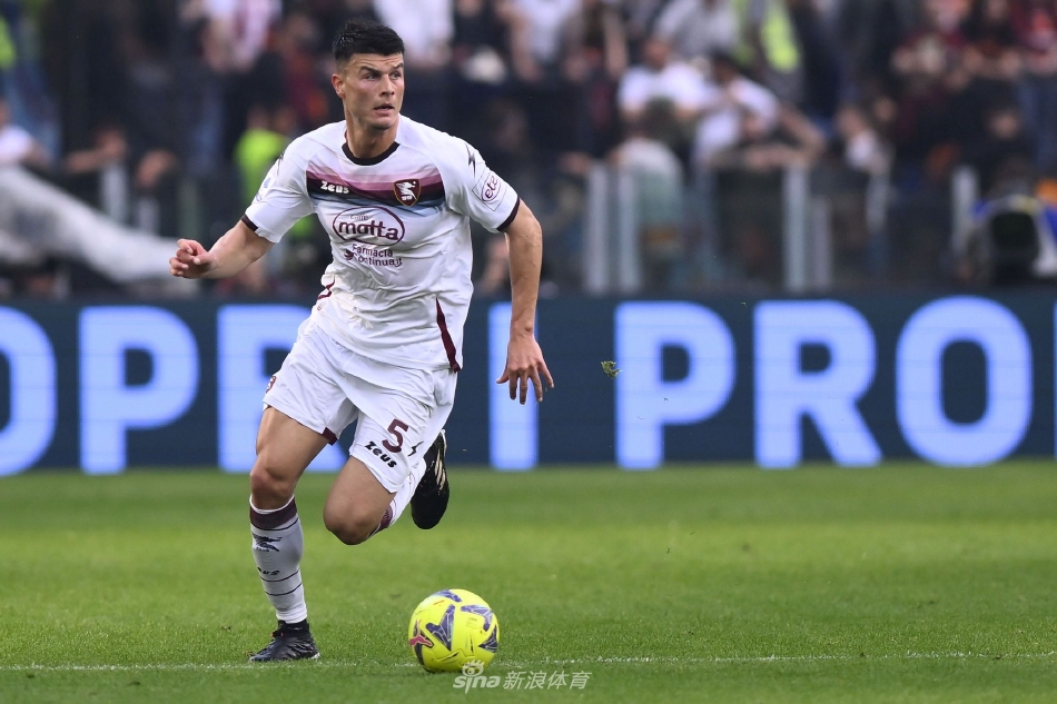 看台上一位罗马小球迷身穿雨衣，手托脸颊凝望球场，眼神中充满了与年龄不符的专注与复杂情绪