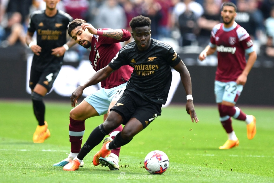 萨卡在比赛中进球后张开双臂滑跪庆祝，身后是沸腾的酋长球场看台，激情与荣耀在此刻完美融合