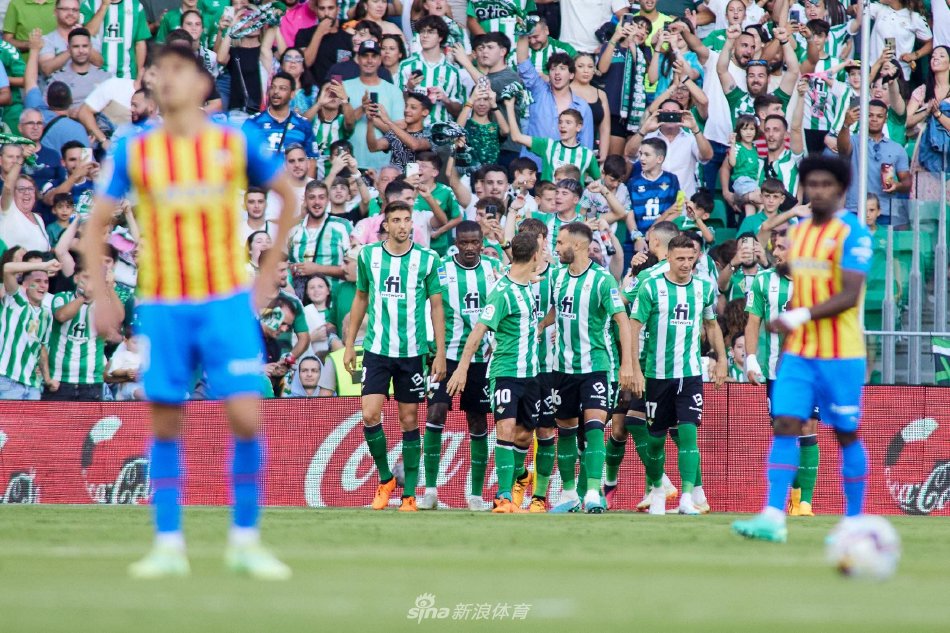 看台上一位小球迷身穿贝蒂斯球衣，眼神专注而充满憧憬地凝望着球场，那是足球希望与传承的象征。