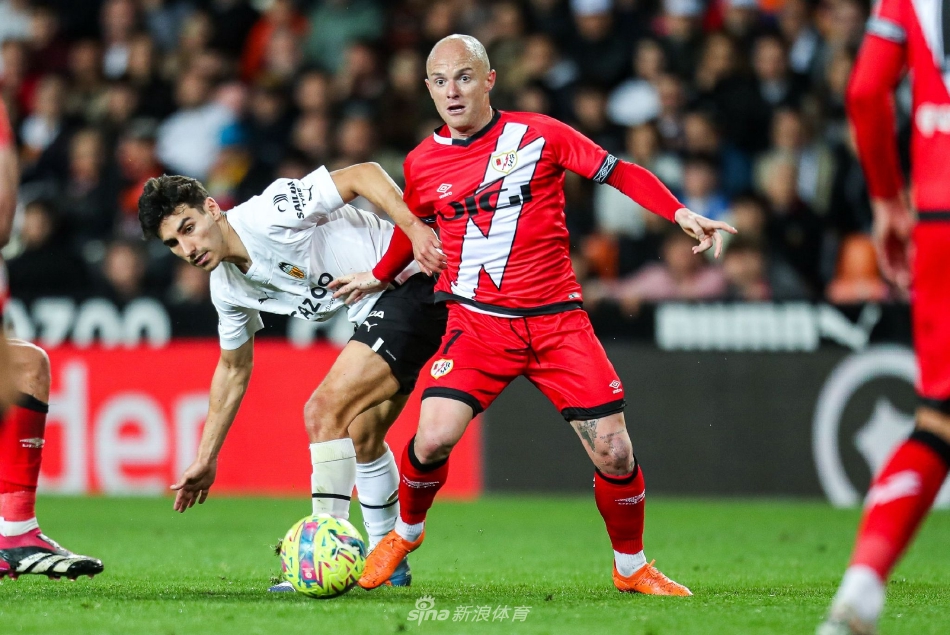 巴列卡诺球员破门瞬间，皮球直窜网窝，守门员奋力扑救却鞭长莫及，背景是呆若木鸡的主队后卫。