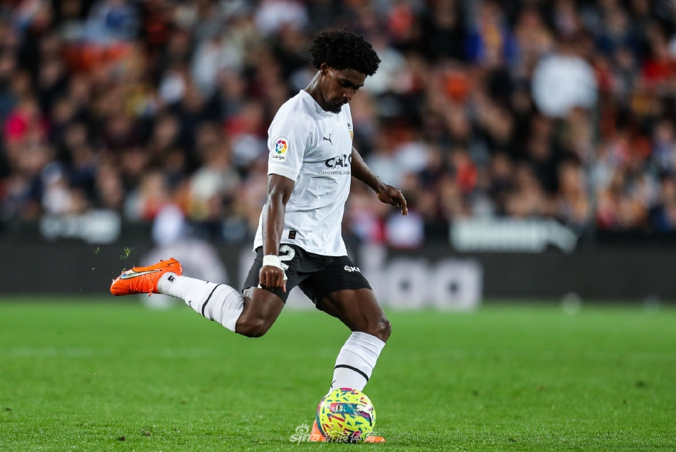 巴伦西亚球员带球突破两名防守队员，身体倾斜，展现出极强的爆发力和平衡感，球场草皮在脚下飞溅。