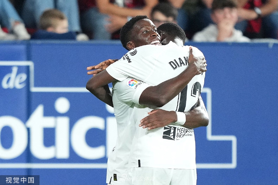 萨达尔球场全景，看台上坐满了身着红蓝球衣的奥萨苏纳球迷，氛围热烈，大战一触即发。