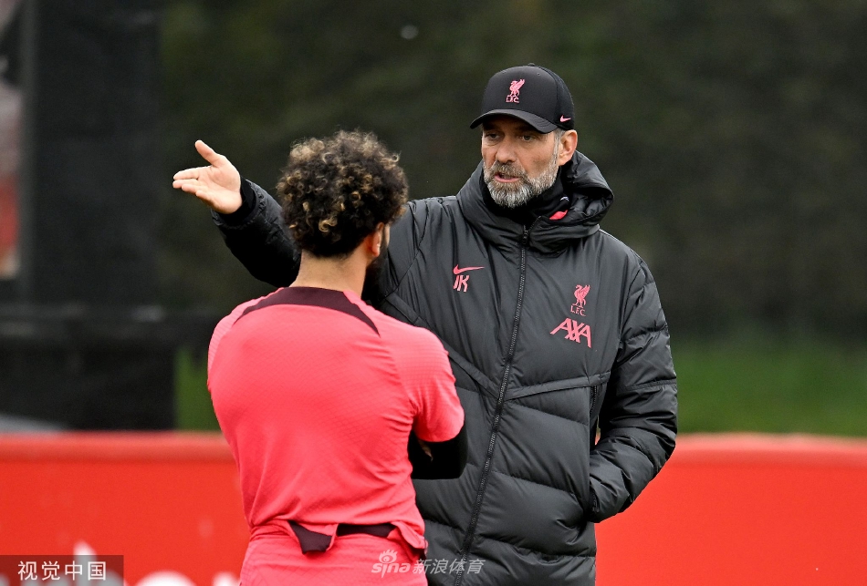 克洛普与萨拉赫在训练场边单独沟通，主帅手势坚定，萨拉赫侧耳倾听，阳光拉长了他们的身影