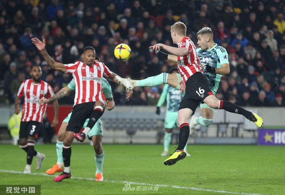 布伦特福德球员延森打入第三球后滑跪庆祝，激动地握拳怒吼，身后是欢呼的队友。