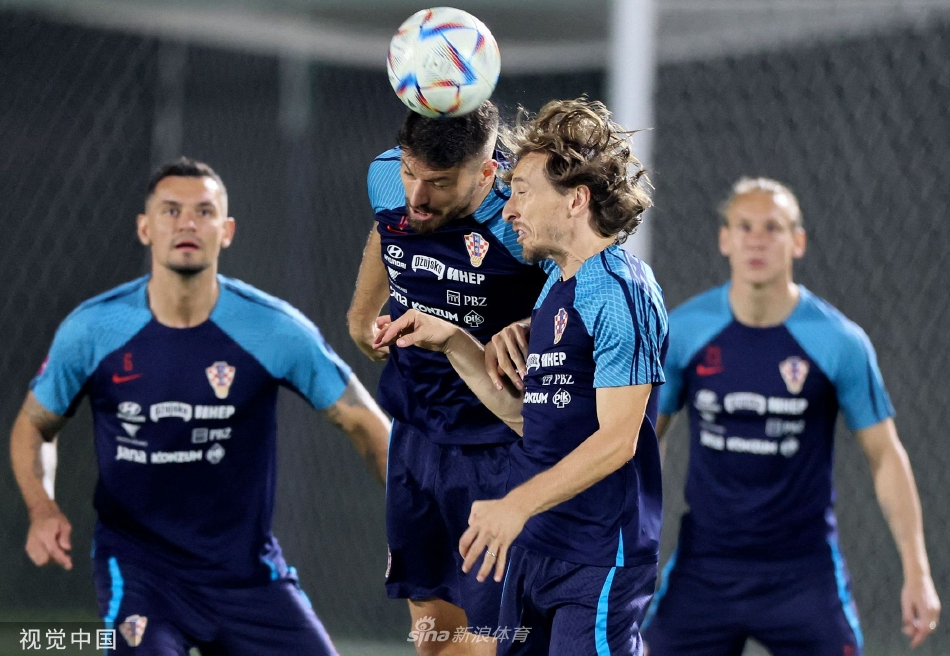 团队之心在跃动：克罗地亚全队围成一圈进行抢圈训练，橙色训练衫与绿色草皮形成鲜明对比，足球在快速传递中化作一道虚影，展现了团队高度的专注与迅捷的协作。