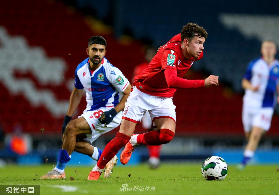 杰西·林加德张开双臂在球场边滑跪庆祝，脸上洋溢着灿烂笑容，身后是欢呼的队友和失望的对手。