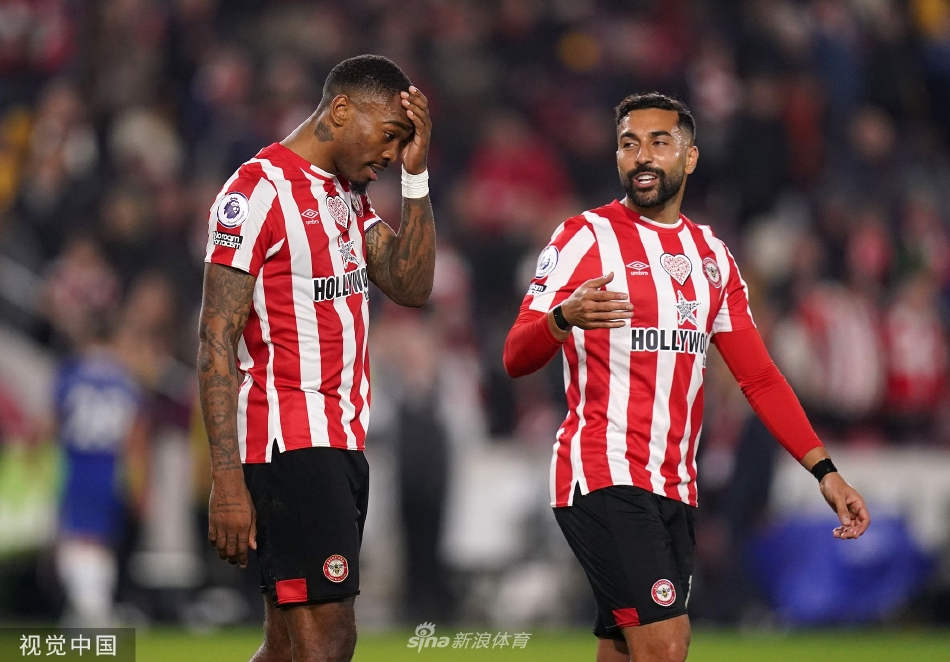 切尔西前锋哈弗茨在布伦特福德两名防守球员的包夹下艰难起脚射门，表情专注且充满力量。