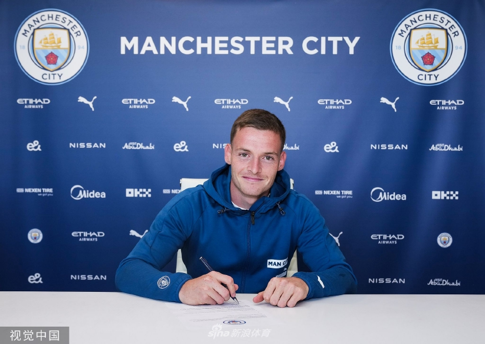 阳光下的戈麦斯举起曼城围巾向球迷致意，眼中闪烁喜悦光芒