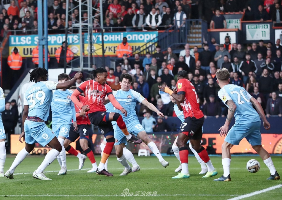 卢顿主帅爱德华兹在场边握拳怒吼指挥，神情专注而激昂，身后是紧张关注赛事的替补席。