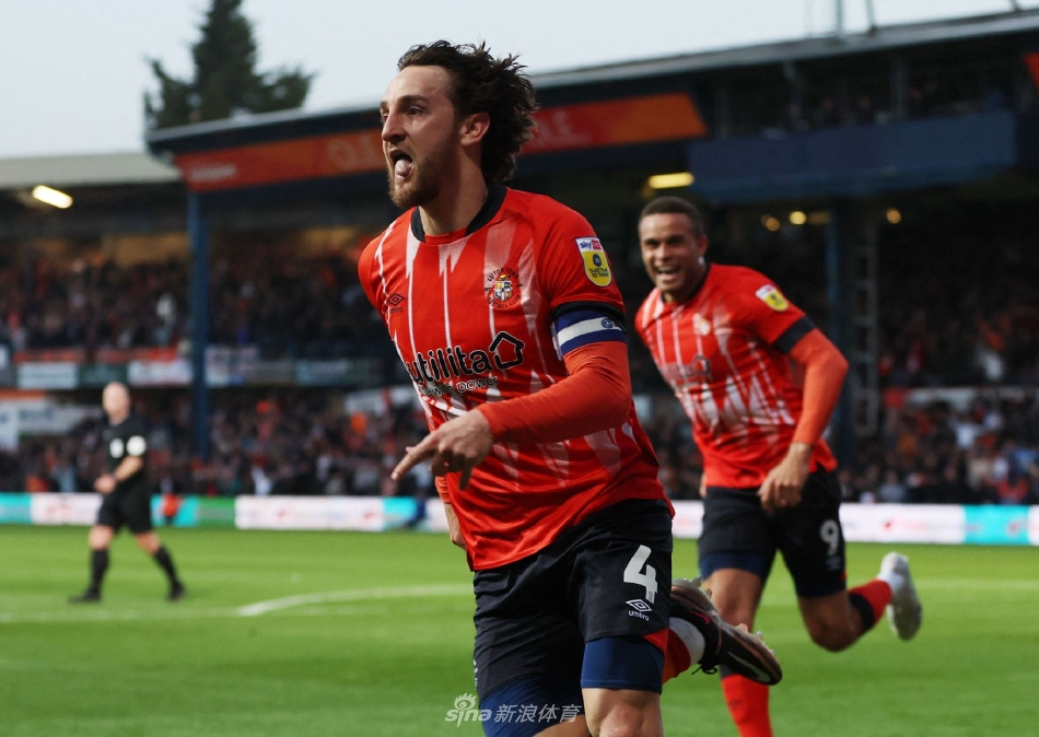 卢顿队长洛克耶在攻入关键头球后，张开双臂奔向角旗区疯狂庆祝，身后是激动万分涌向场边的球迷。