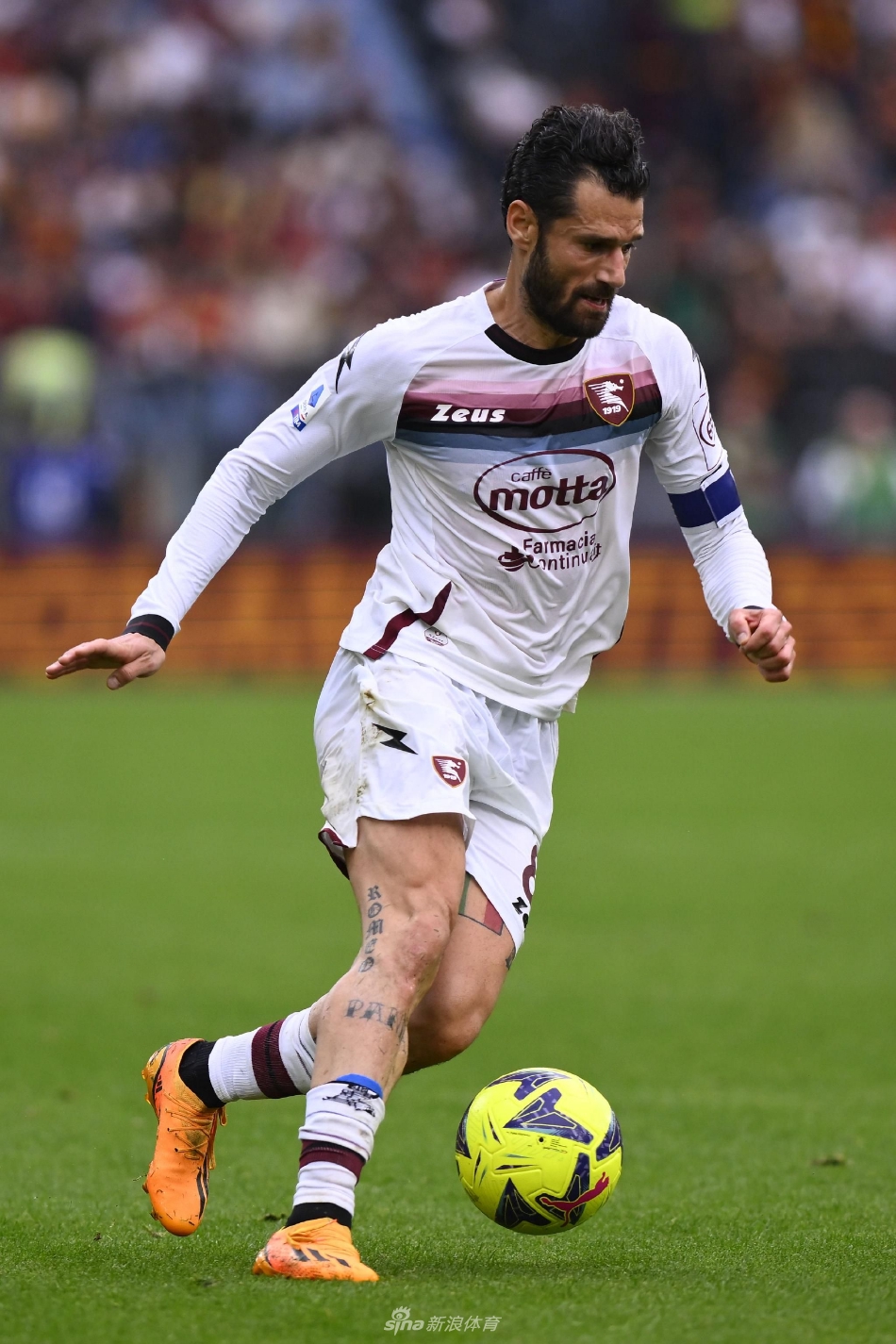 萨勒尼塔纳球员坎德雷瓦张开双臂在雨中激情滑跪庆祝，背景是模糊的罗马防守球员沮丧的身影