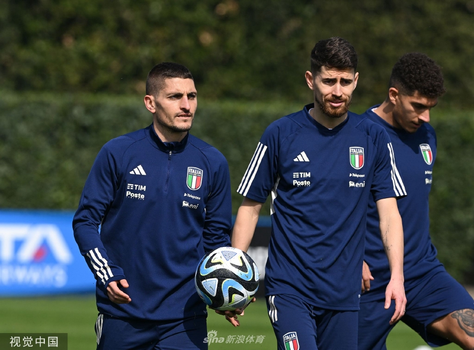 主教练曼奇尼神情专注，在场边与教练组成员热烈讨论战术板，阳光洒在草坪上映出长长的影子。