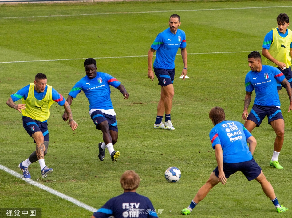 两名意大利球员在训练间隙互相击掌鼓劲，背景中其他队员正在进行传接球练习