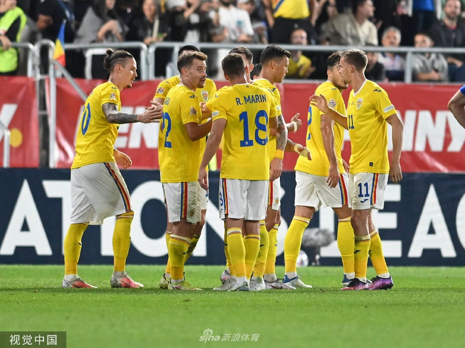 罗马尼亚队球员丹尼斯·曼在进球后张开双臂激情奔跑庆祝，他的身后是欢呼雀跃的队友和沸腾的看台。