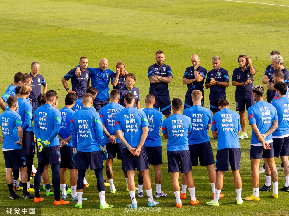 曼奇尼亲自为全队示范传球动作要领，球员们围成一圈专注聆听，背景是秋日湛蓝的天空