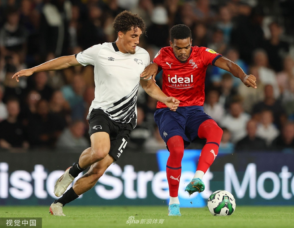 德比郡主教练在场边神情专注，紧握双拳指挥比赛，眼神中充满了对胜利的渴望与坚定。