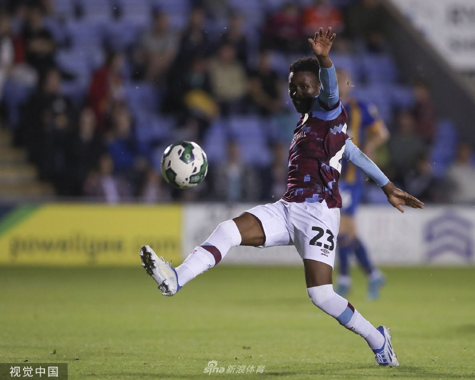 夜幕下的球场灯光璀璨，双方球员在场上激烈对抗，身影被灯光拉长