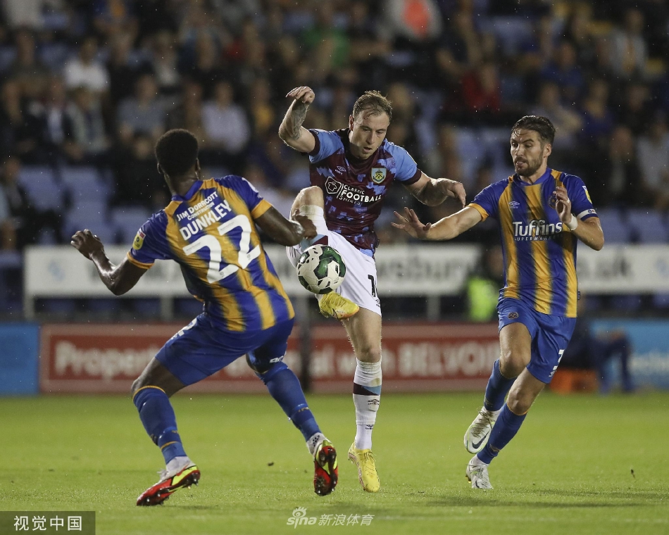 什鲁斯伯里球员在防守中高高跃起，奋力头球解围，身后是密切关注战况的队友