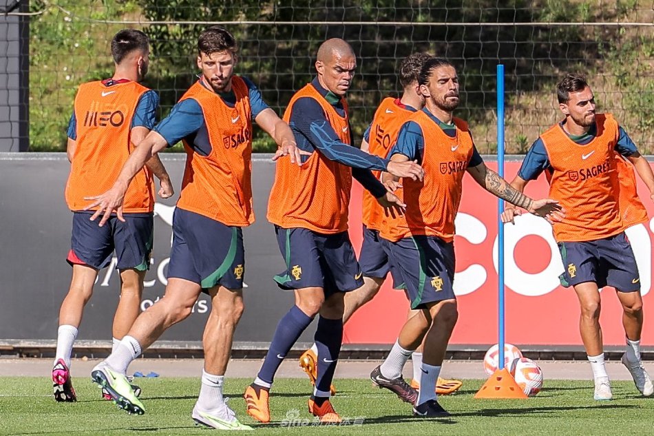 球员们在绿茵场上进行高速折返跑训练，汗水在阳光下闪烁，体现了高强度的体能储备过程。