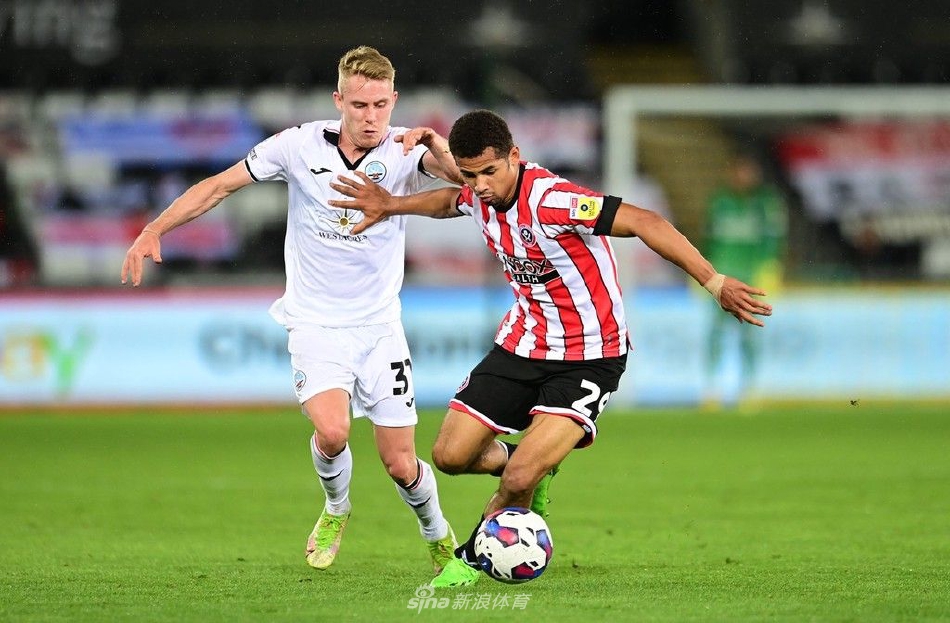 谢菲尔德联球员激动地拥抱庆祝制胜进球，背景是看台上失望的斯旺西球迷，悲喜两重天的画面极具感染力。