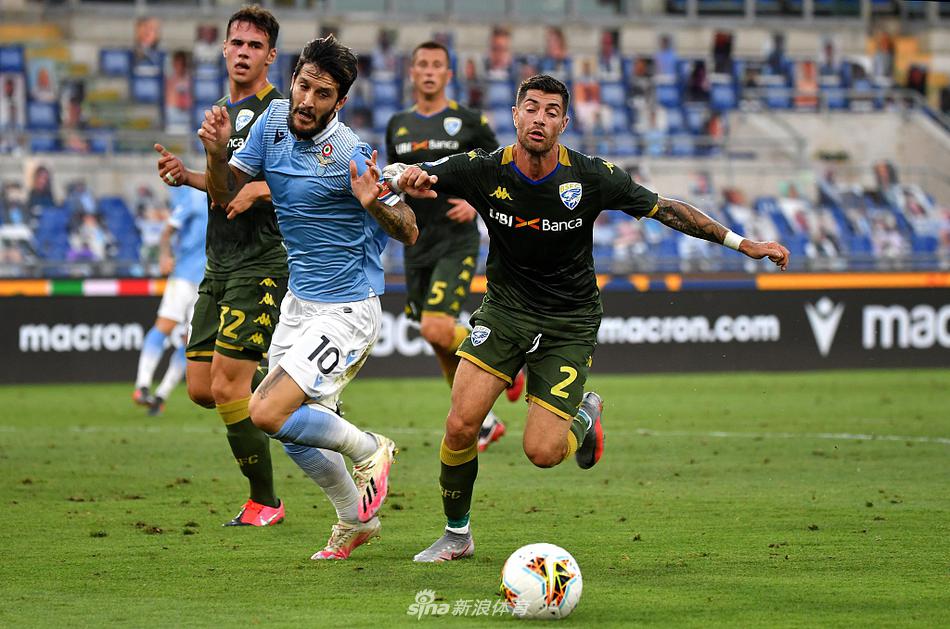 拉齐奥的中场核心路易斯·阿尔贝托在拼抢中全力争顶，他面部肌肉紧绷，眼神坚定，湿透的战袍紧贴在身上，凸显了比赛的激烈与球员的投入。