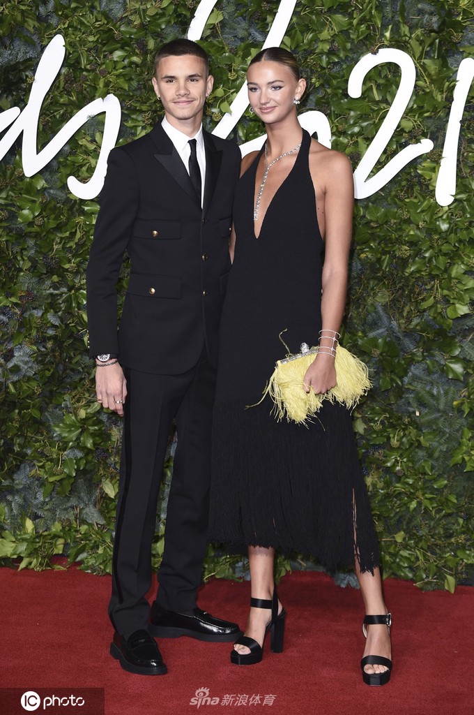 在红毯的背景板前，这对璧人默契地摆出造型，米娅的黑色流苏裙摆与罗密欧的西装裤腿在风中轻轻触碰。他们紧握的双手和脸上洋溢的自信笑容，仿佛在宣告属于新一代的时尚偶像已经诞生。