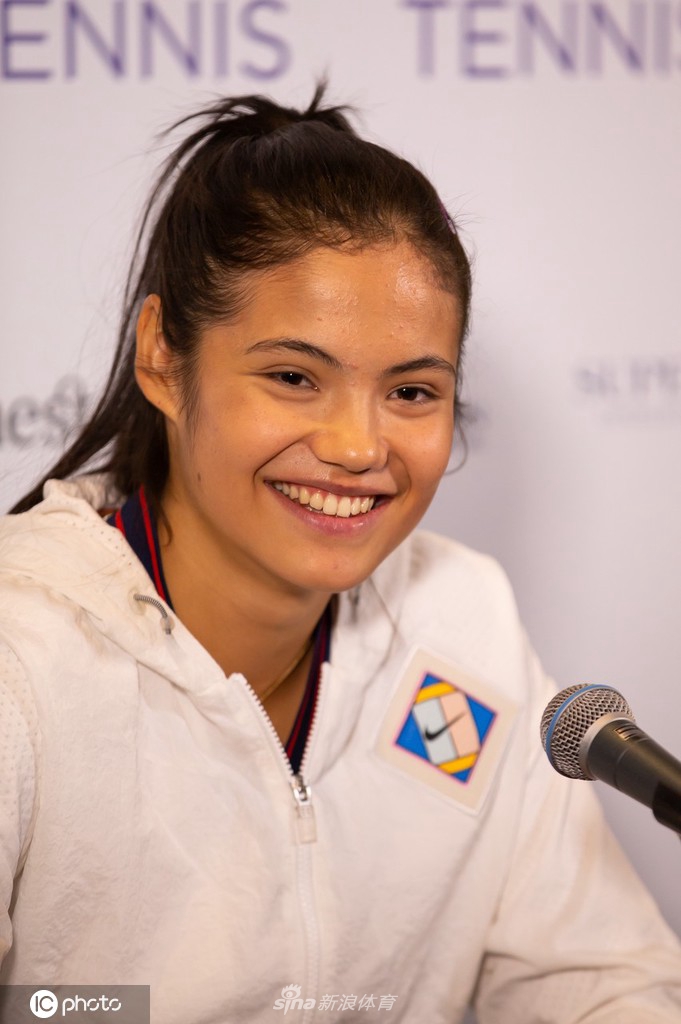 新科美网冠军拉杜卡努在伦敦表演赛后的新闻发布会上，身着一袭简约的黑色内搭，微笑着侧头聆听记者提问，眼神中流露出超越十九岁年纪的从容与淡定。