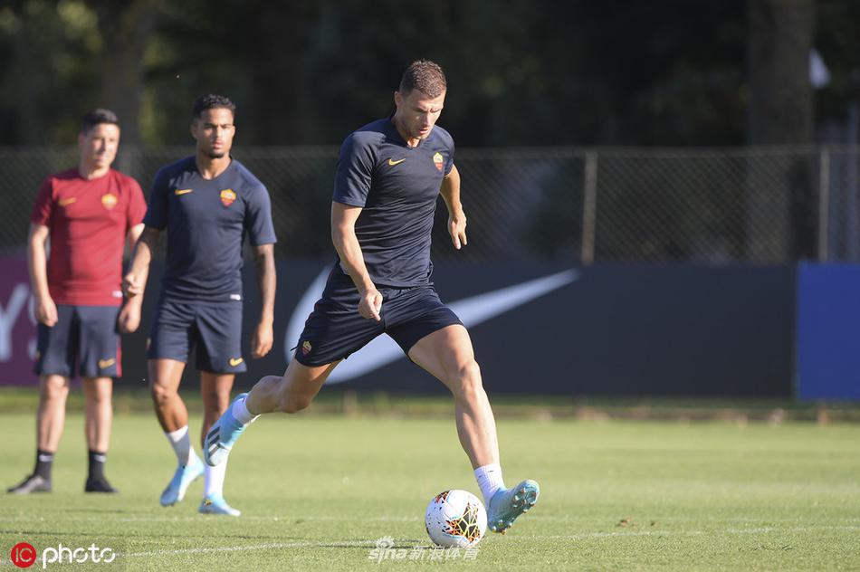 主教练丰塞卡在场边手持战术板，神情严肃地向扎尼奥洛等队员讲解跑位，身后是夕阳下的训练场，战术革新正在进行