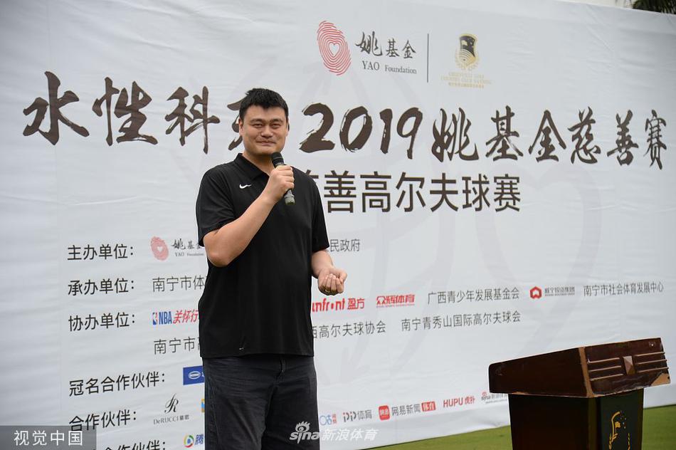 姚明与一位小球手在果岭上亲切互动,他微微俯下身,巨大的身影与孩童形成温馨对比,画面充满了对下一代成长的关怀与鼓励