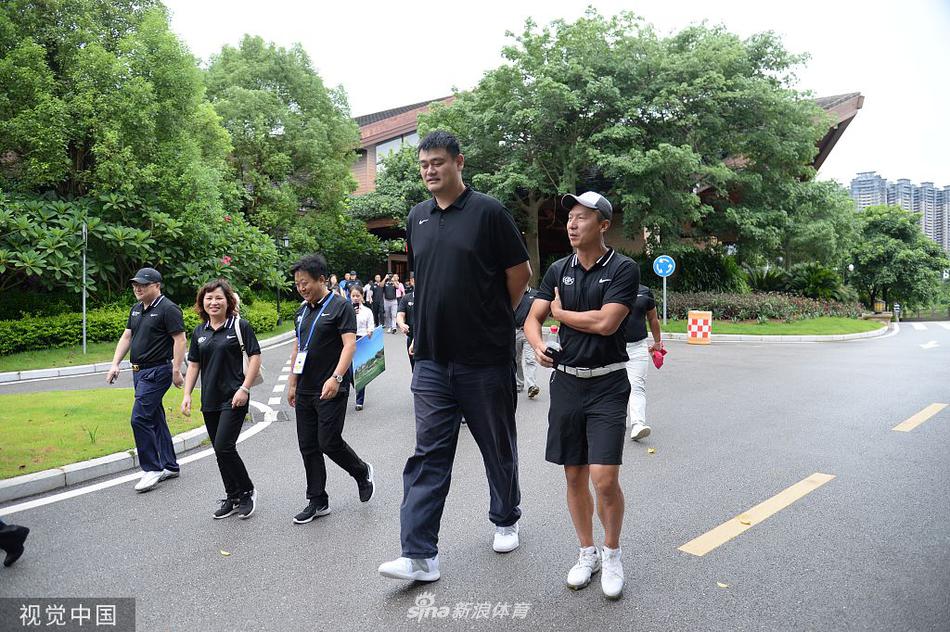 姚明与几位企业家球友在发球台合影留念,他面带微笑站在中间,身后的蓝天白云映衬着慈善赛轻松而又充满正能量的氛围