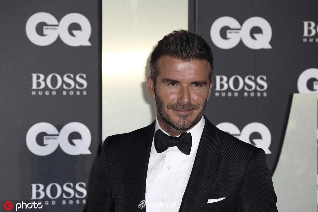 维多利亚·贝克汉姆身着简约干练的白色套装，挽着丈夫的手臂，冷酷而优雅的气场与身边的布鲁克林形成温馨对比。