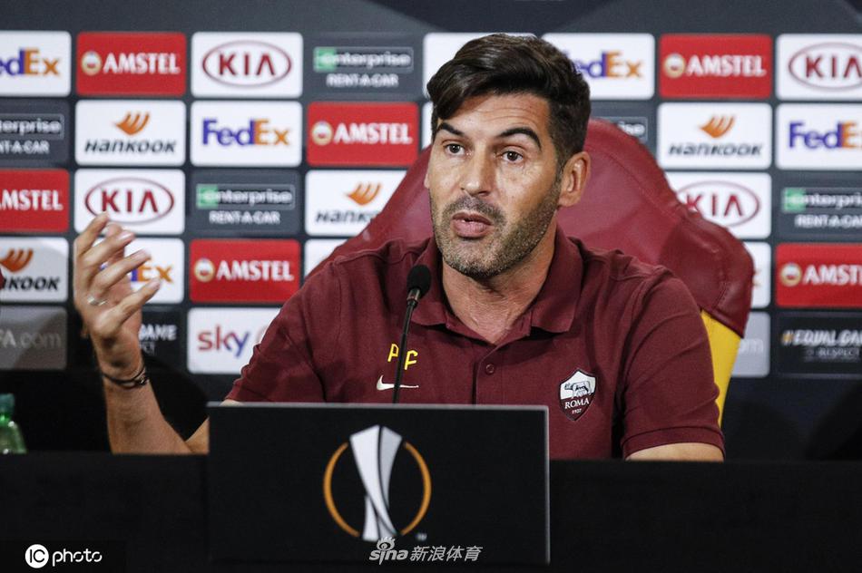 罗马主帅丰塞卡在新闻发布会上目光坚定，双手轻握，向在场的记者们阐述着球队的战术理念，背景是清晰的罗马队徽。