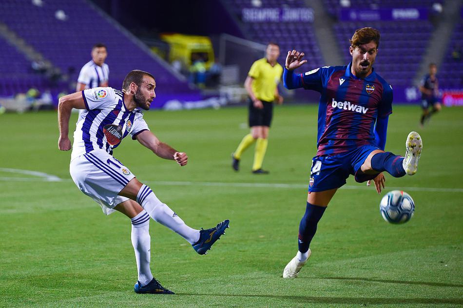 巴拉多利德中场核心背身护住皮球，他张开双臂抵挡着身后莱万特防守球员的凶猛逼抢，面部肌肉因发力而紧绷，眼神则冷静地观察着队友的跑位，试图在包夹之下为球队找出唯一的传球线路。