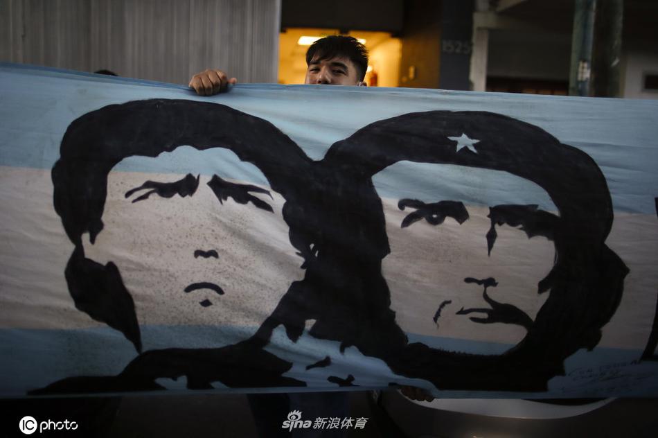 一名小球迷骑在父亲的肩膀上，费力地将一幅手绘的马拉多纳画像举过头顶，画中的马拉多纳正露出标志性的笑容。