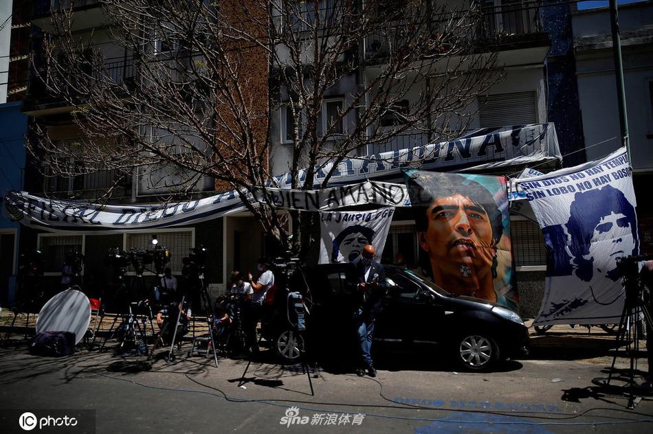 数名安保人员手拉手组成人墙，试图维持秩序，但他们的身后是望不到尽头的球迷队伍，每个人都踮起脚尖，试图从远处捕捉医院的一点动静。