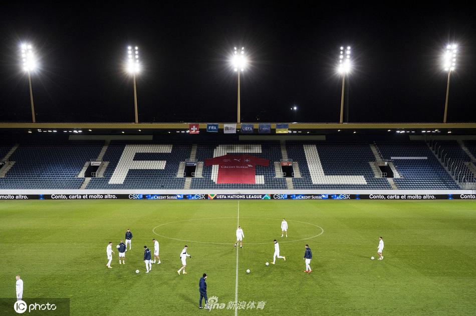 夕阳的余晖洒在训练场上，一名球员正在进行射门练习，皮球应声入网。他身后的队友们正在慢跑调整，整个画面充满了赛前特有的宁静与张力。