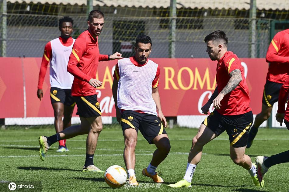 罗马的清晨阳光洒在训练场上，球员们正在进行分组抢圈，皮球在红黄背心之间快速传递，扬起细微的草屑