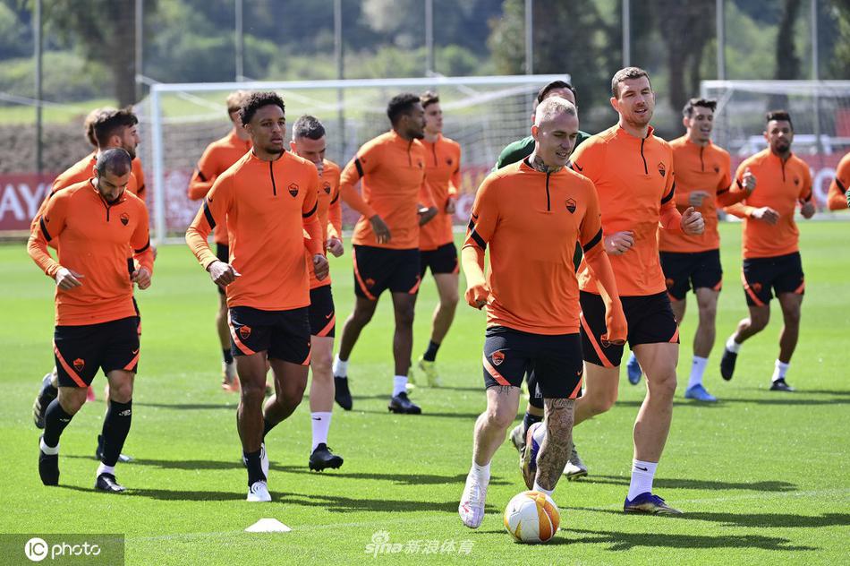 在罗马特里戈里亚训练基地，宽阔的绿茵场上，罗马将士们正围成紧密的圆圈，进行着战前最后一次热身。队长哲科神情专注，双手抱胸，仿佛在思考明晚如何敲开对手的球门。阳光洒在他们身上，为这场即将到来的恶战镀上了一层温暖却紧张的光晕。